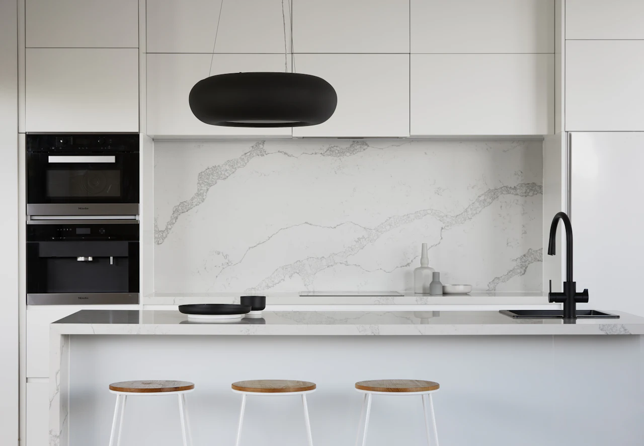 White kitchen with a softly veined white countertop and backsplash