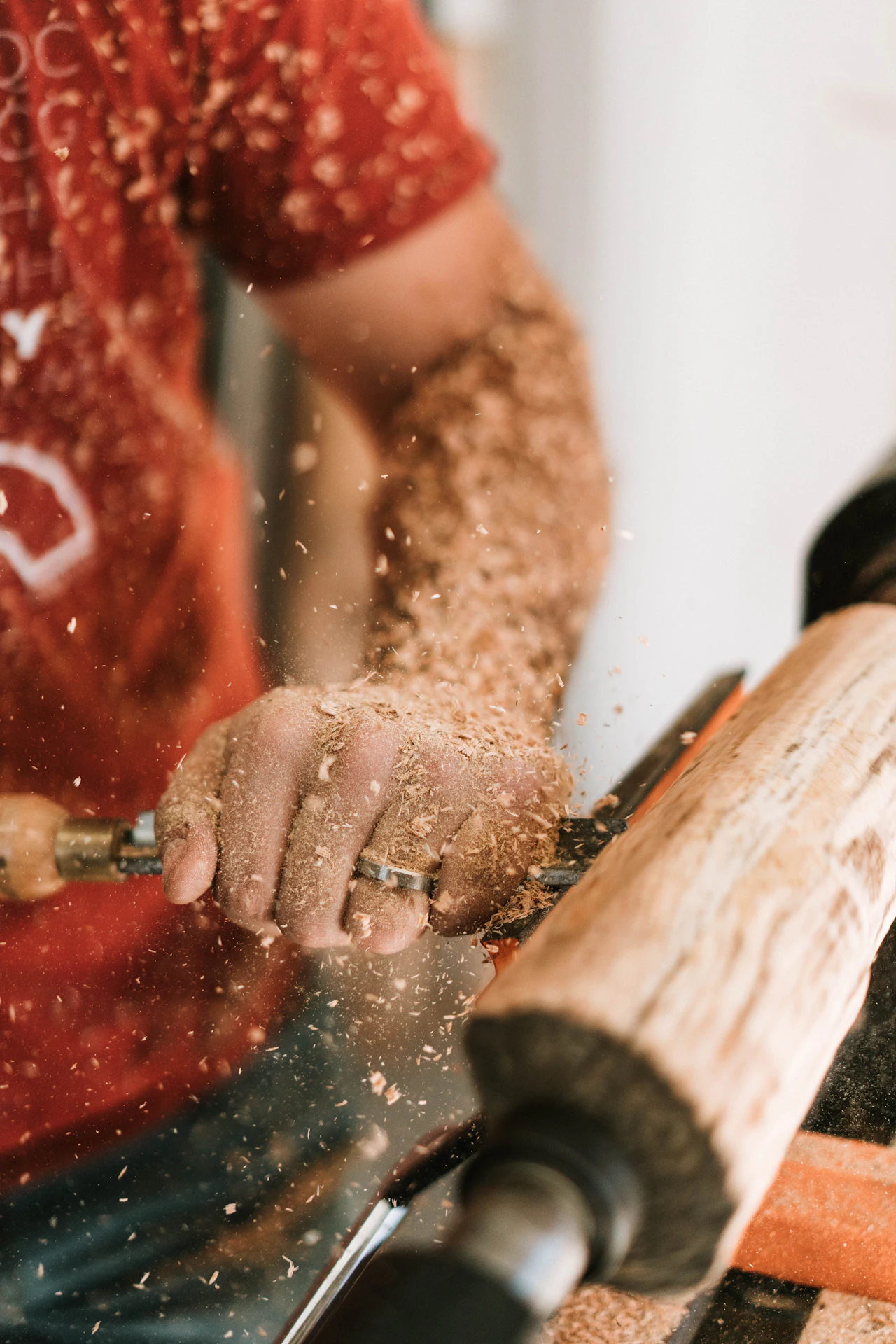 Close view of hands shaping wood with fine shavings