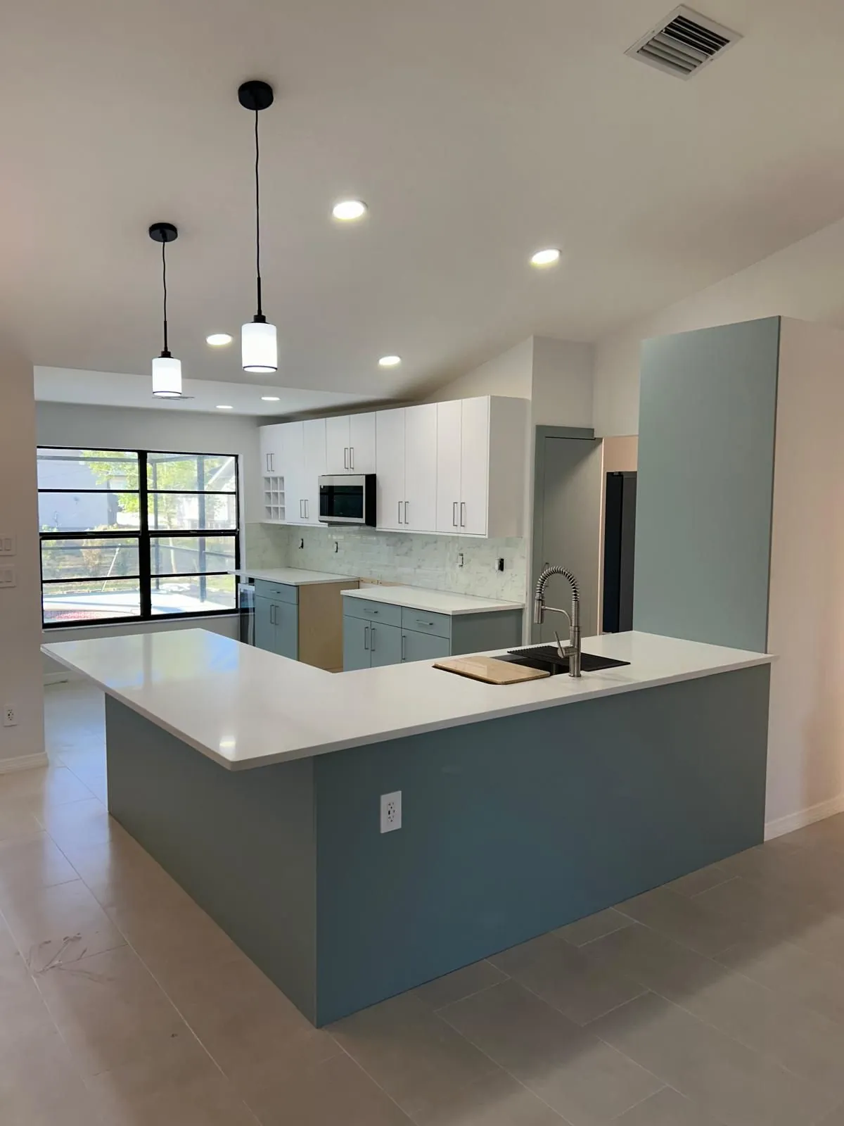 Kitchen with soft blue base cabinets, white uppers and a white peninsula