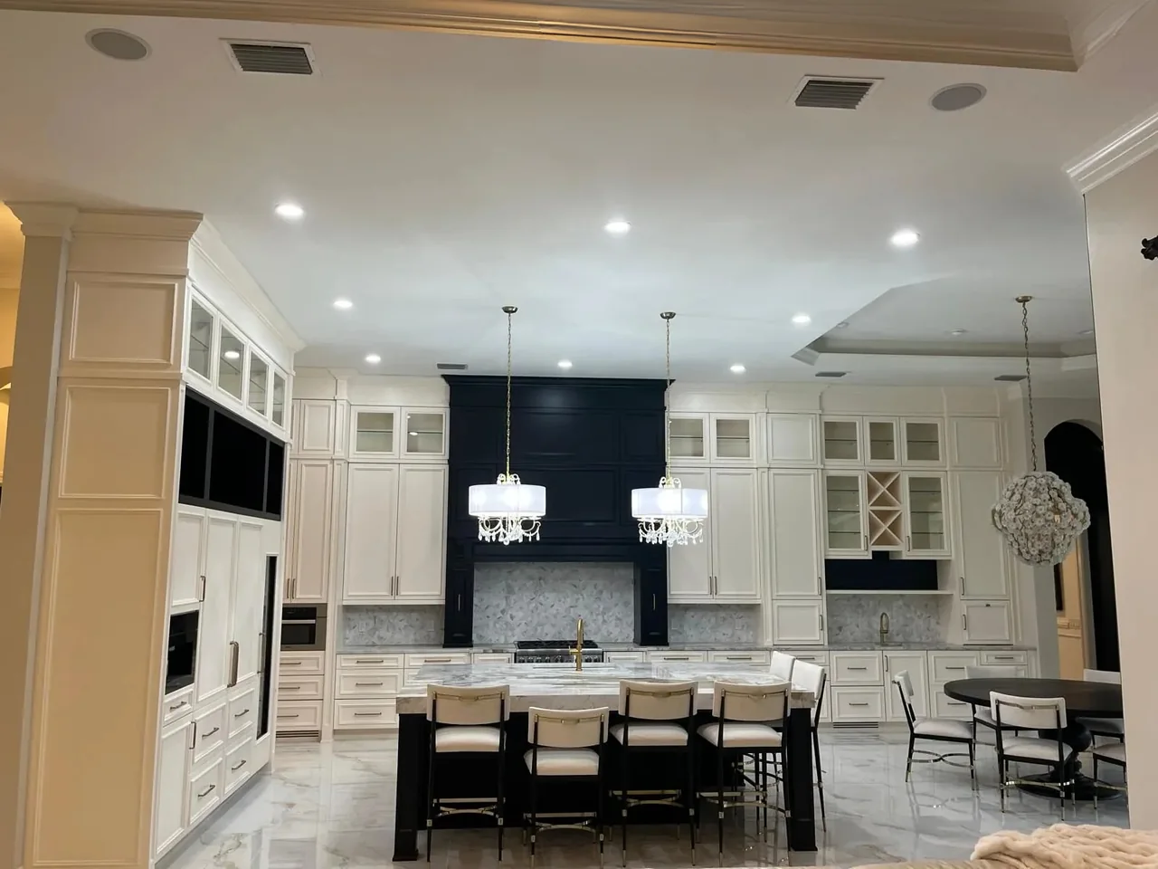 Large kitchen with cream cabinetry, a black range hood and a black island