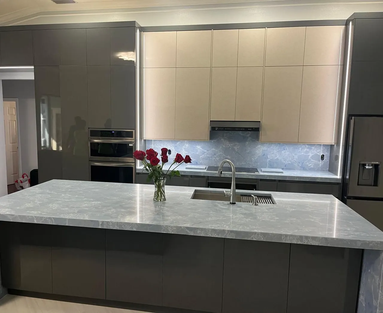 Grey high-gloss kitchen with a blue stone waterfall island