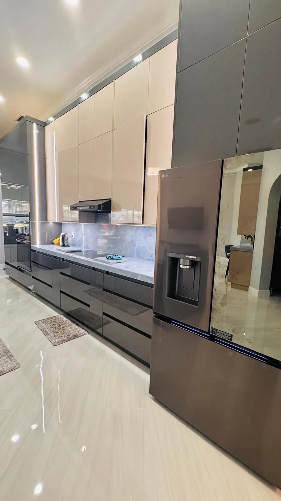 Full-height grey and cream gloss cabinets with a blue stone backsplash